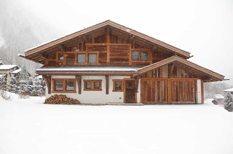 an image of a chalet under strong snow