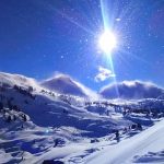 image of sun blazing down on snow resort