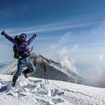 man celebrating on top of a snowy mountain