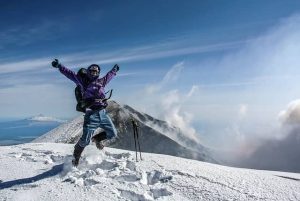 man celebrating on top of a snowy mountain